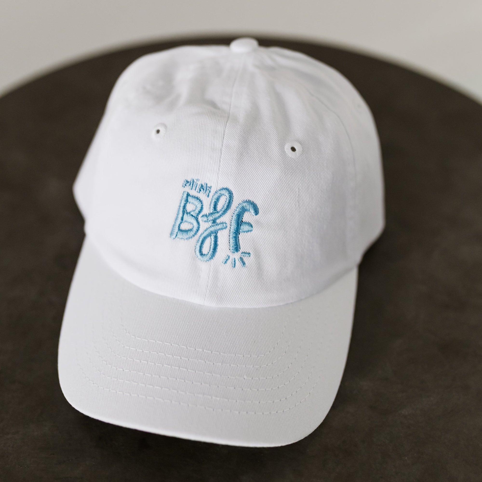 white baseball cap with light blue embroidered thread reading "Mini BFF" for toddlers