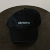 navy  baseball cap embroidered with light blue thread "Solopreneur" on a table