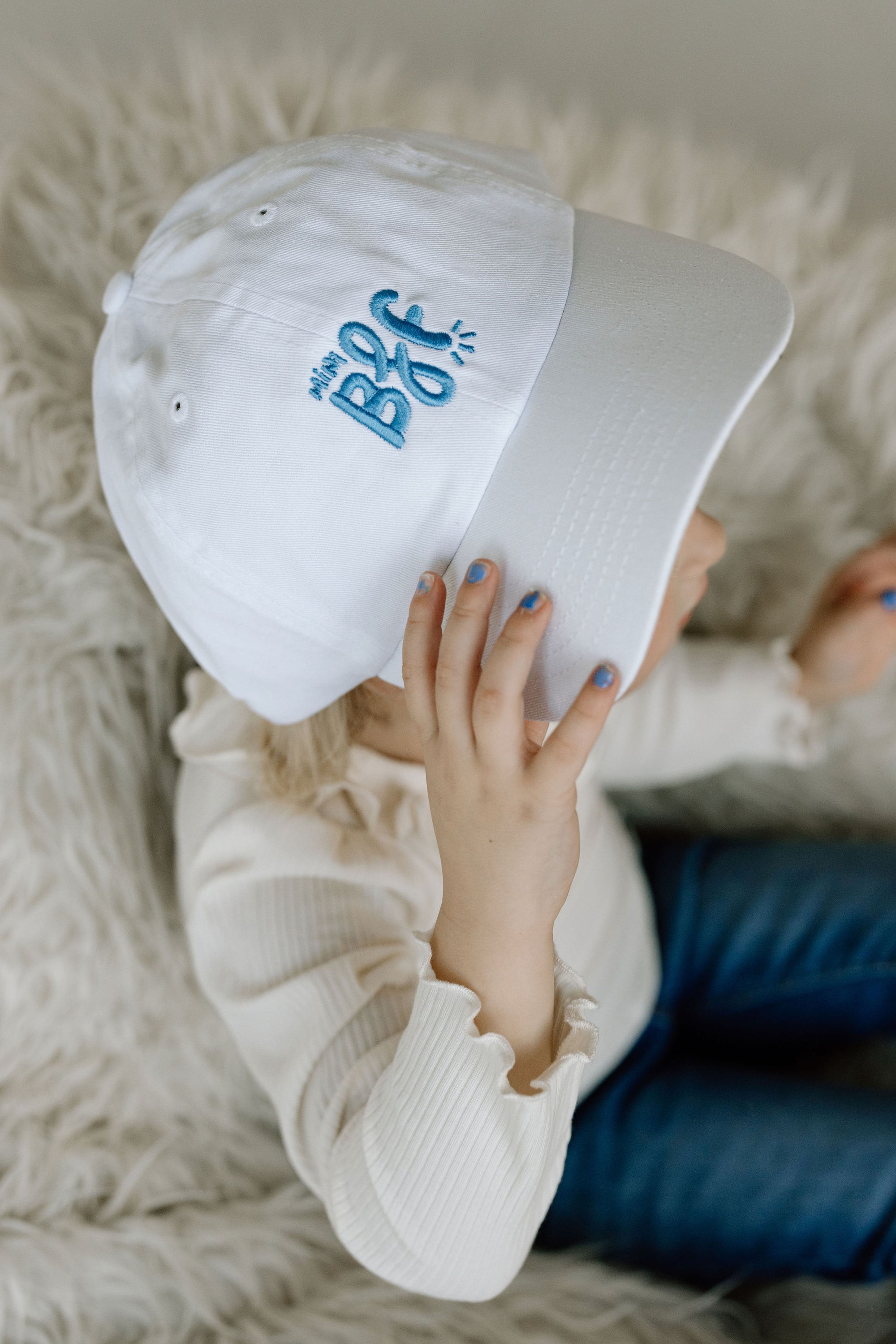 toddler girl wearing white baseball cap with light blue embroidery saying mini bff
